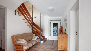 Ein Wohnzimmer mit einer Holztreppe, einem Sofa, einem Schrank und einer Tür zu einem anderen Raum.