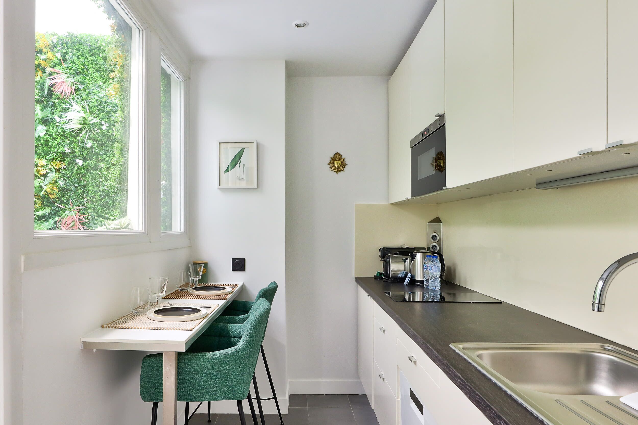 A compact kitchen with a dining area, a window with a view of greenery, and a microwave on the counter.