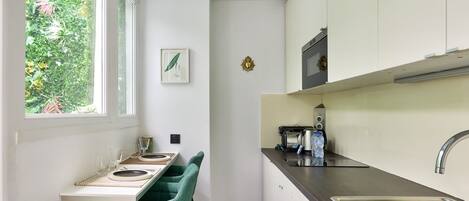 A compact kitchen with a dining area, a window with a view of greenery, and a microwave on the counter.