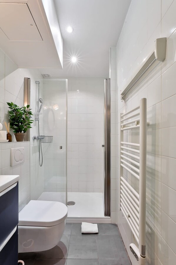 A modern bathroom with a glass-enclosed shower, a toilet, and a built-in sink.