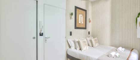 Un dormitorio moderno con cama, mesitas de noche, lámpara colgante y un cuadro enmarcado en la pared.