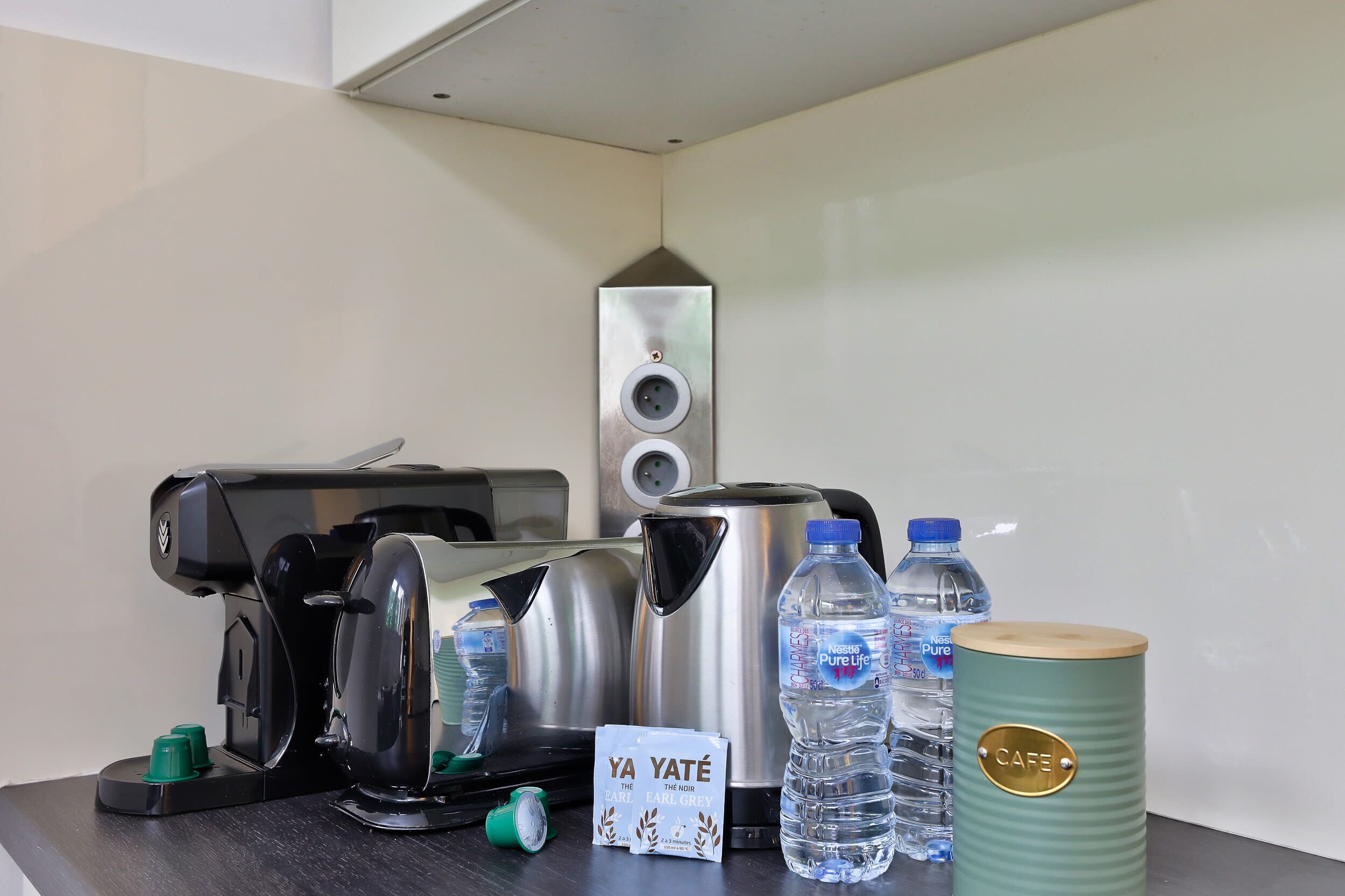 A coffee maker, kettles, water bottles, a branded water bottle, and a branded container on a table.