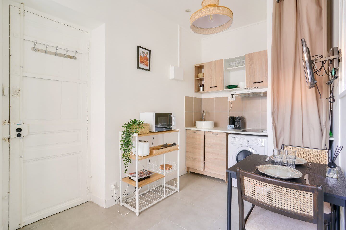Une cuisine compacte comprenant un coin repas, un lave-linge et une petite table à manger avec des chaises.