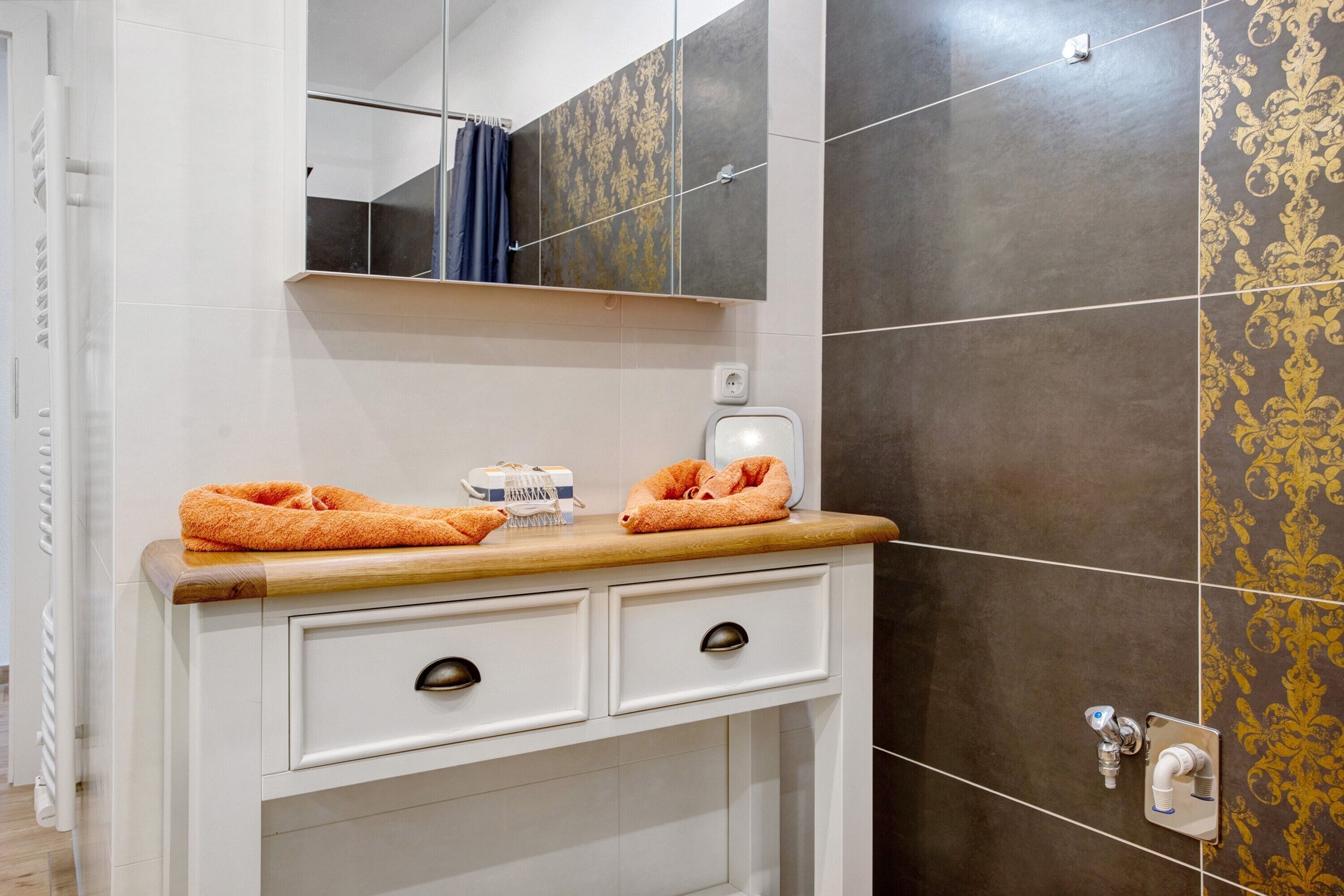 A bathroom with a white vanity, two drawers, a mirror, and a towel rack.