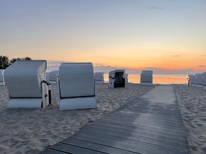 Une promenade en bord de mer agrémentée de chaises longues en osier et d’une terrasse en bois.