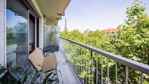 Un balcon avec vue sur la Tour Eiffel, une chaise et des plantes en pot.