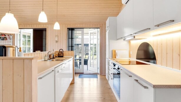 A modern kitchen with wooden cabinets, a central island, pendant lighting, and a view to the outside. - "Felicia" - 350m from the sea by Interhome (Gedser)