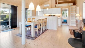 A spacious living area with a wooden ceiling, a dining table with chairs, a kitchen area, and a fireplace. - "Felicia" - 350m from the sea by Interhome (Gedser)