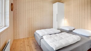 A room with wooden walls and floors, a bed with grey bedding, a white wardrobe, and a hanging light fixture. - "Felicia" - 350m from the sea by Interhome (Gedser)