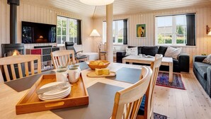 A cozy cabin interior with a dining area, a sofa, a fireplace, and large windows. - "Felicia" - 350m from the sea by Interhome (Gedser)