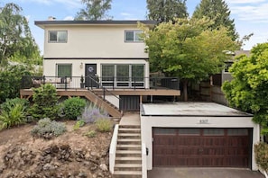 A two-story house with a garage, a deck, and a staircase leading to the deck.