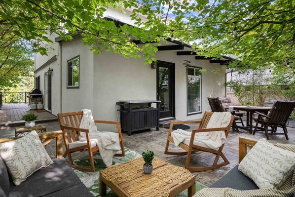 An outdoor patio with wooden furniture, a grill, and a covered seating area.