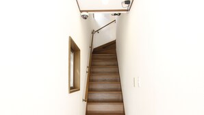 A wooden staircase with a handrail, a small window on the left, and a light switch on the wall. - 203_Shinjuku Gourmet&Shopping Recently (新宿区)