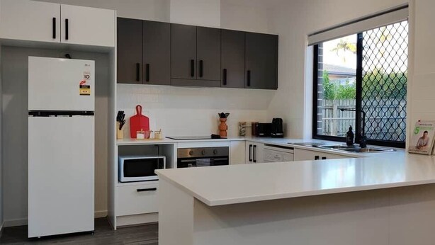 Eine moderne Küche mit weißen Schränken, einem eingebauten Backofen und einem großen Fenster.