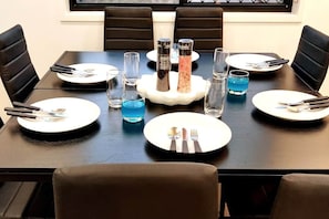 A dining table set with plates, cutlery, glasses, and salt and pepper shakers.