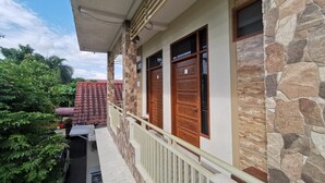 A two-story building with a balcony, stone facade, and wooden doors.