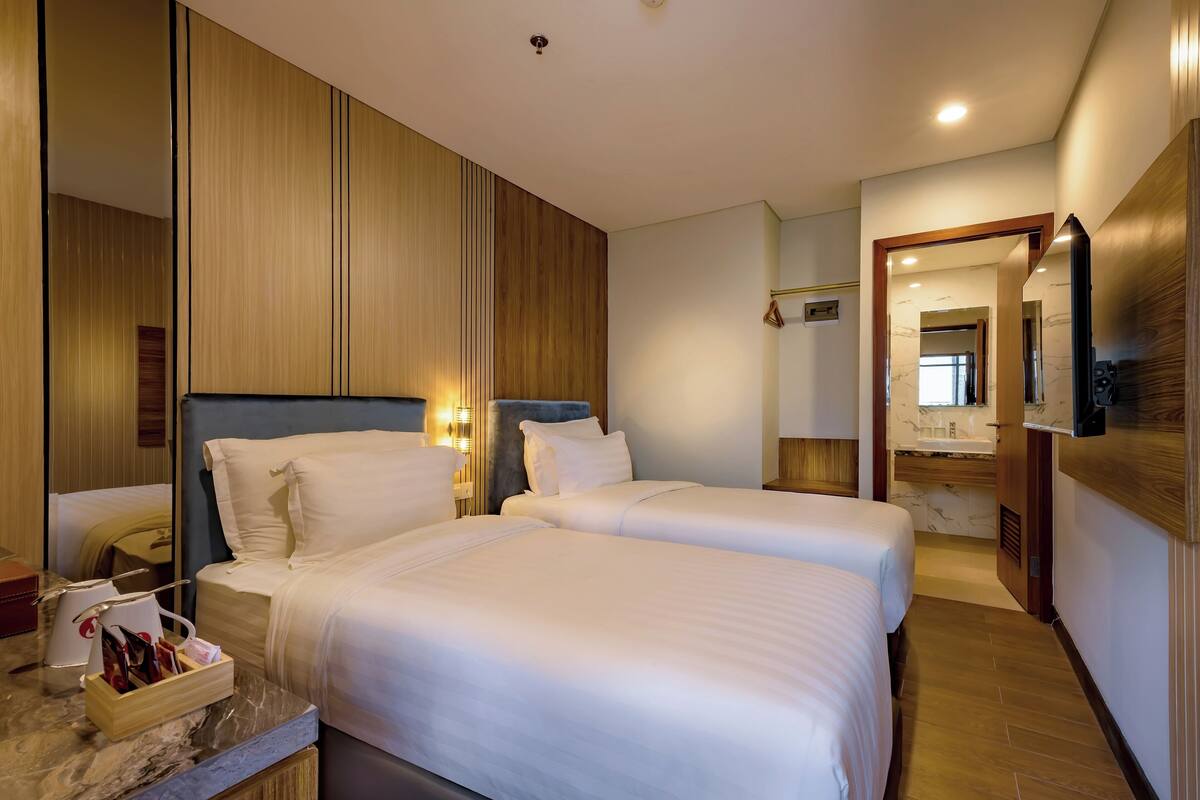 Ein Hotelzimmer mit zwei Betten, einem мраморном Nachttisch und einem Holzschrank.