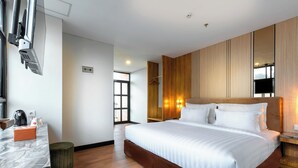 Een moderne hotelkamer met een groot bed, een wand van houten panelen, een marmeren aanrecht en een televisie.