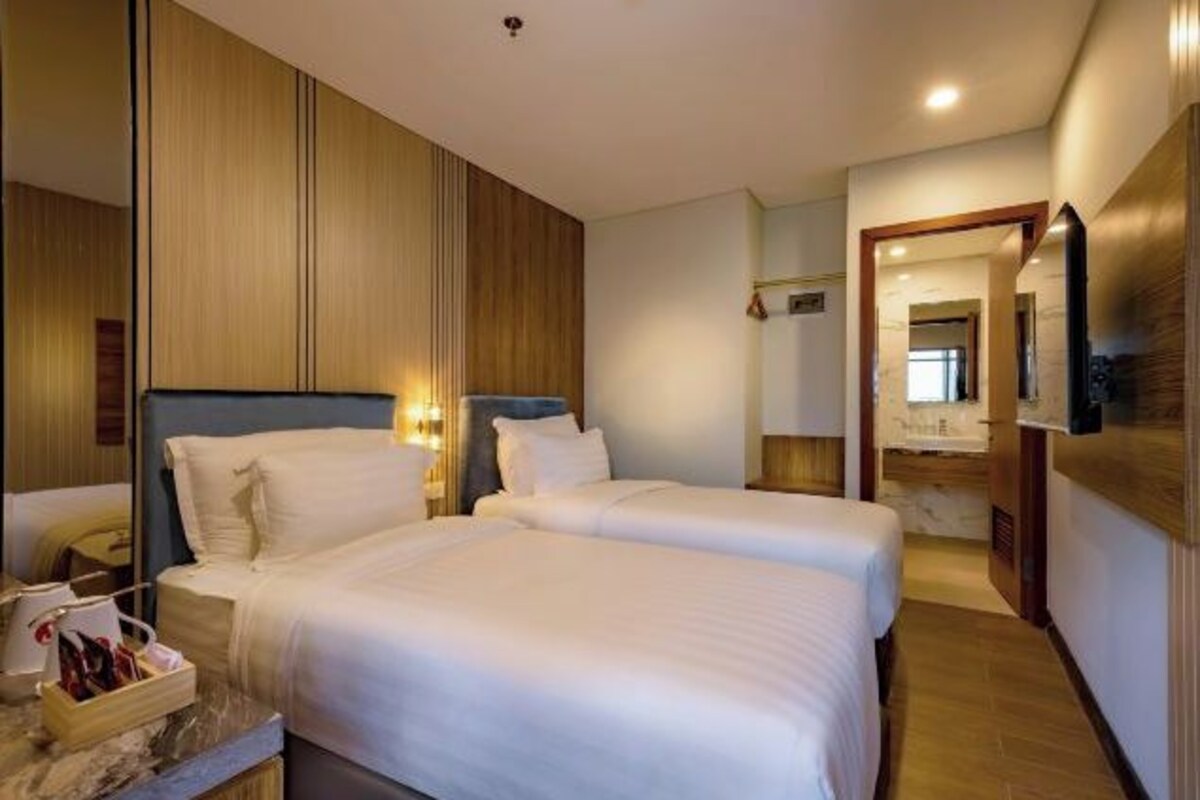 Habitación de hotel con dos camas, un panel de pared de madera, una mesita de noche de mármol y un espejo.