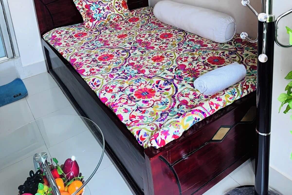Quarto com uma cama, mesa de cabeceira, cadeira, cabideiro e janela.