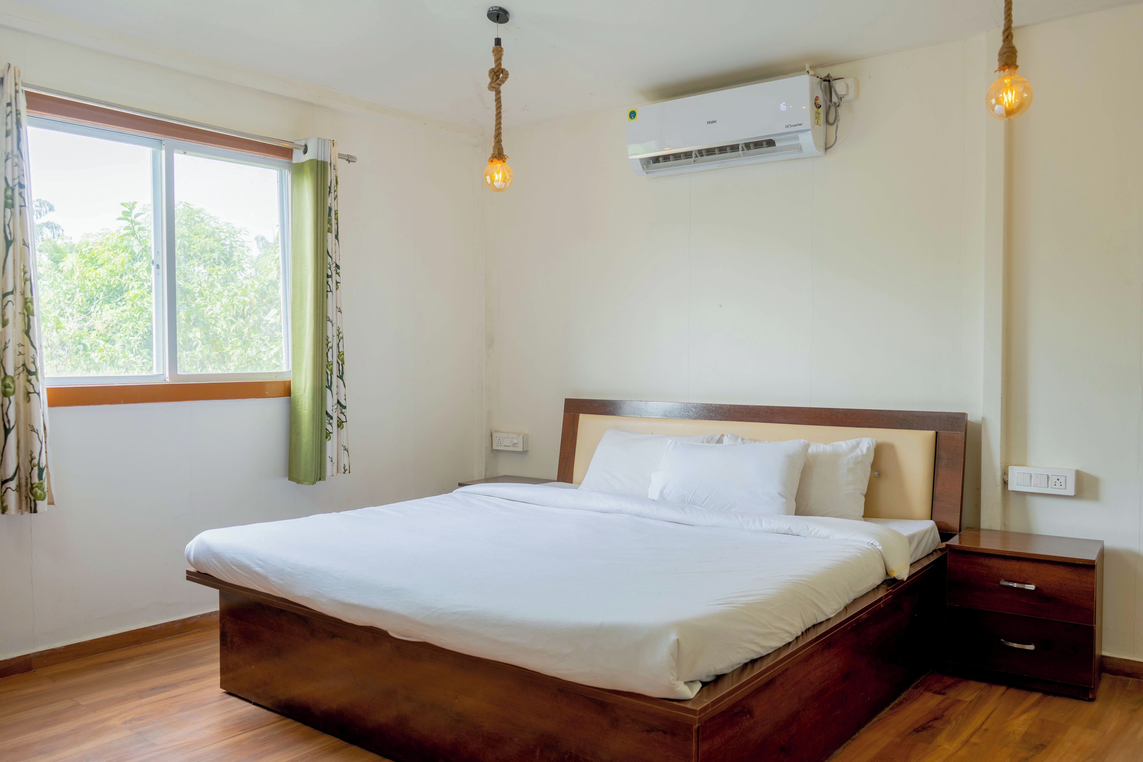 Ein Schlafzimmer mit einem hölzernen Bett, einem Nachttisch, einer Klimaanlage und einem Fenster mit Vorhängen.