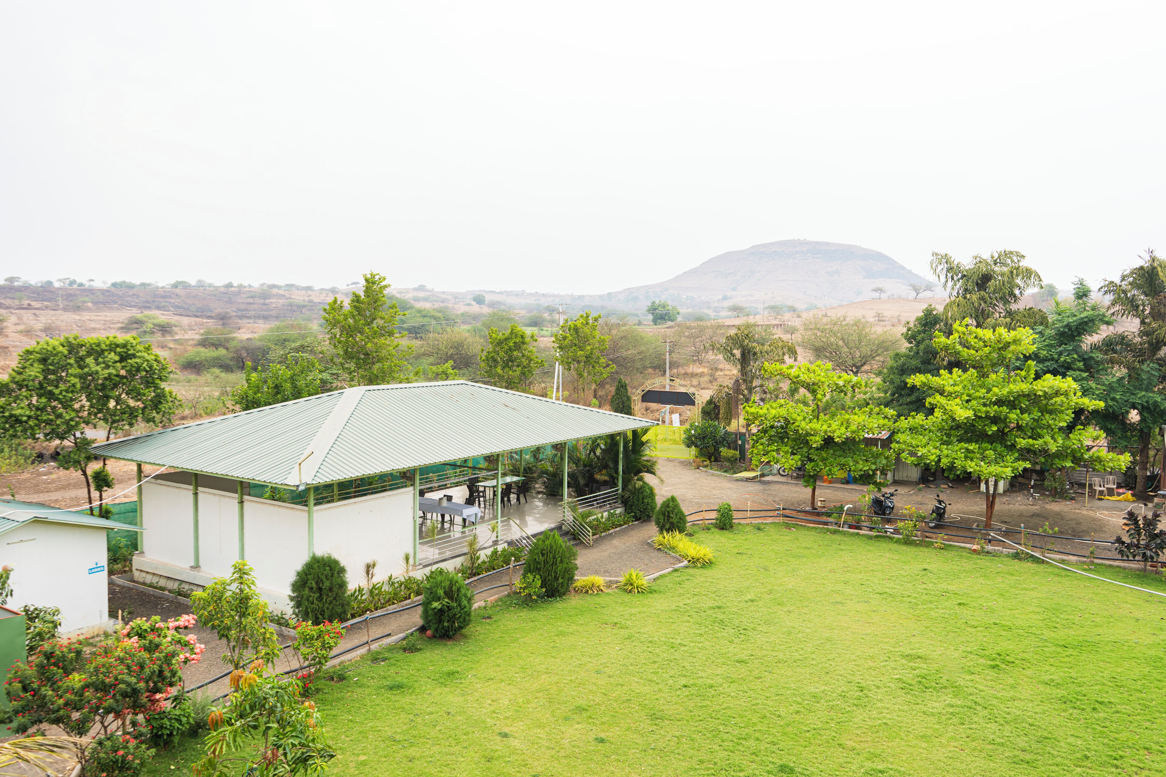 A building with a green roof, surrounded by a grassy area and trees.