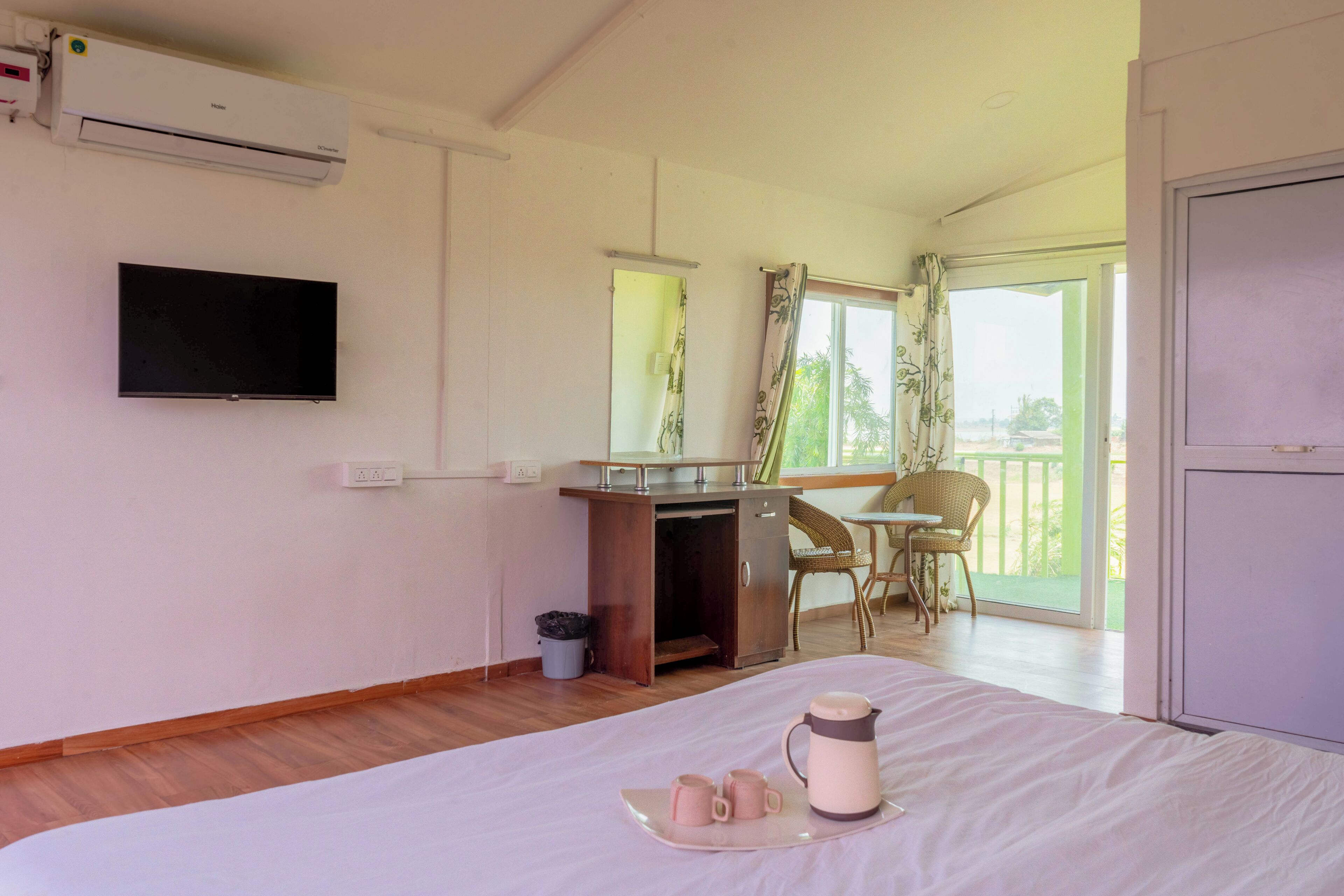 A hotel room with a bed, a desk, a chair, a TV, and a balcony with a view.