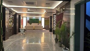 A modern hotel lobby with a reception desk, seating area, and potted plants. - Hotel Mayur Palace (Agra)