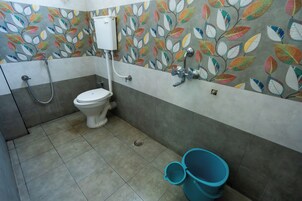 Un baño con inodoro, ducha y un revestimiento de pared con motivos de hojas.