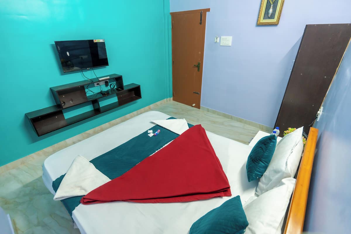 Ein Hotelzimmer mit einem Bett, einem an der Wand montierten Fernseher, einer Holztür und einem Spiegel.
