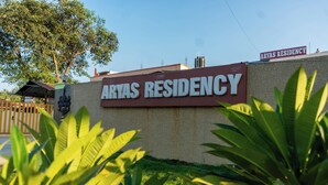 Une enseigne indiquant l’emplacement de la résidence Aryas, offrant une vue dégagée sur la façade de l’immeuble et la végétation environnante.