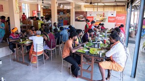 Un espace repas avec plusieurs tables et chaises, un réfrigérateur Coca-Cola et une variété de produits alimentaires exposés.