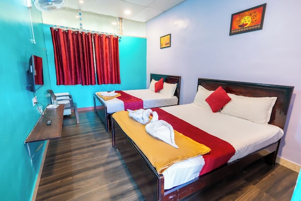 A hotel room with two beds, a desk, and a television. - Aryas Residency (Coimbatore)