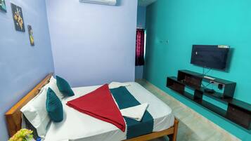 A bedroom with a bed, a TV, and a wall-mounted air conditioner.