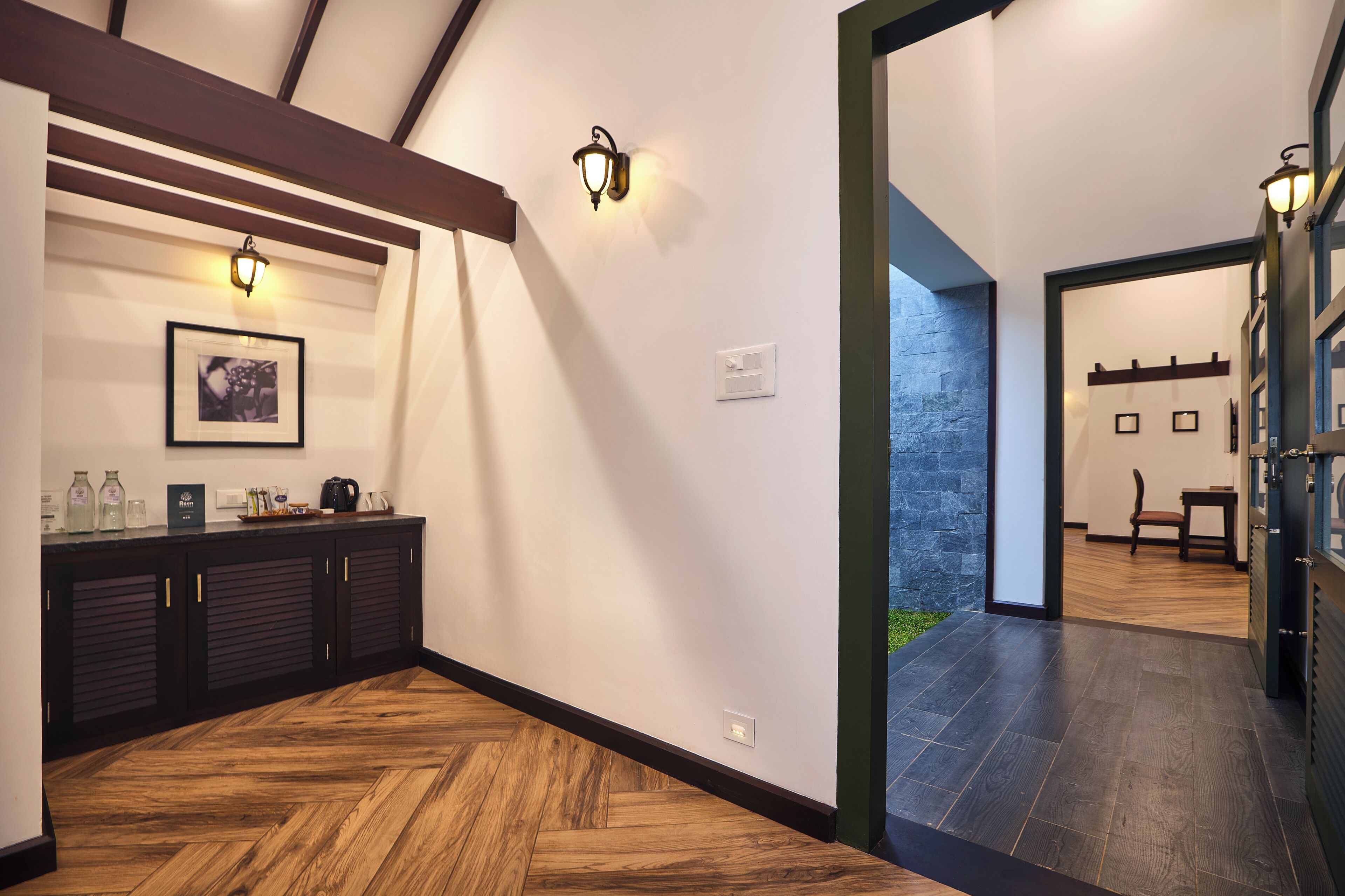 A modern hallway with wooden flooring, dark cabinets, and wall-mounted lighting fixtures.