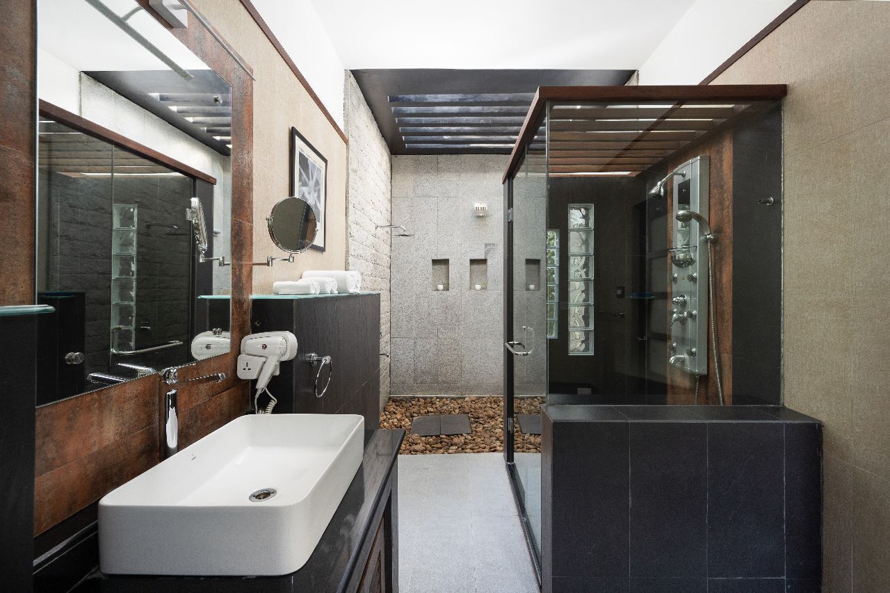 A modern bathroom with a large mirror, a white sink, and a glass-enclosed shower area.