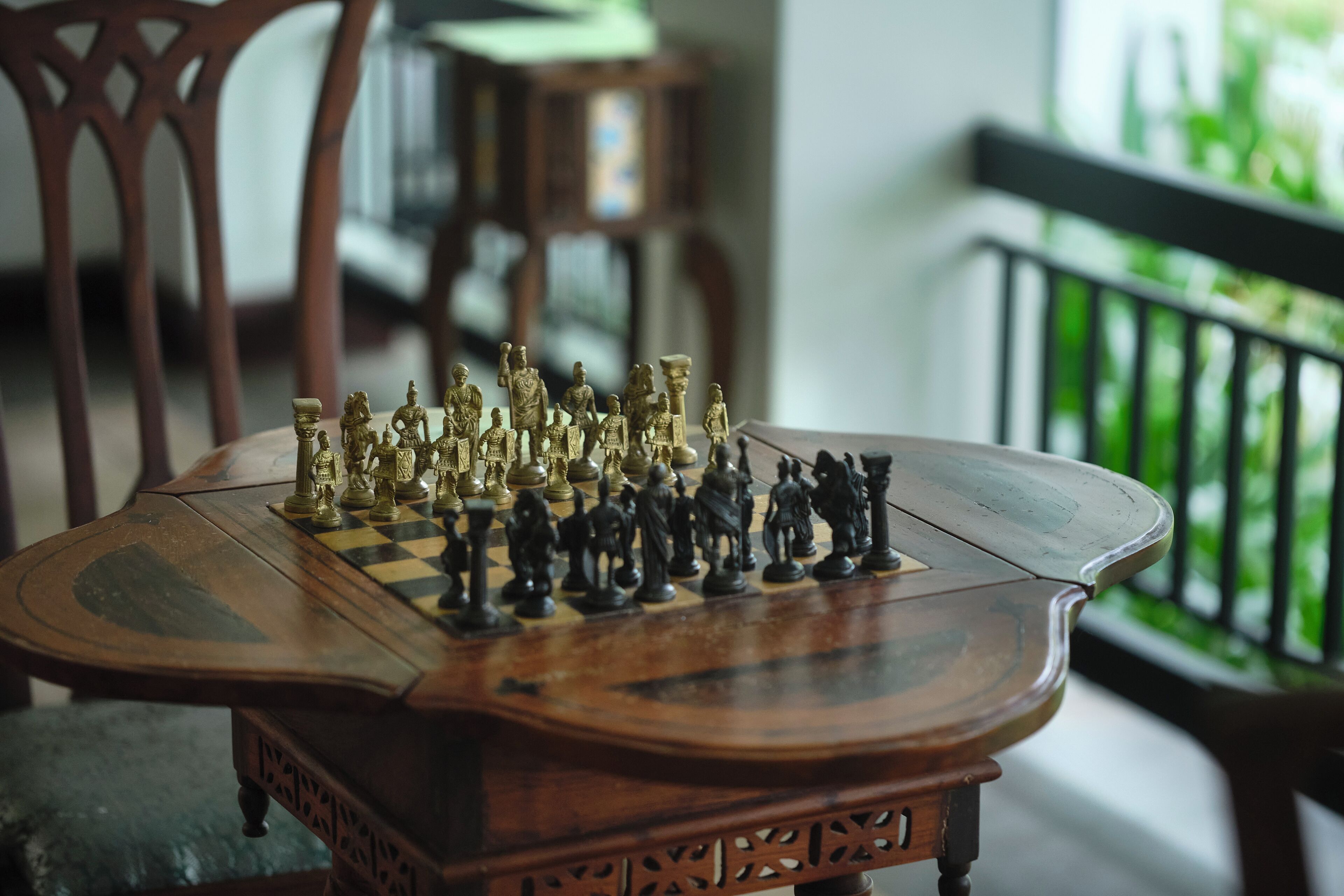 A chessboard with pieces on a wooden table.