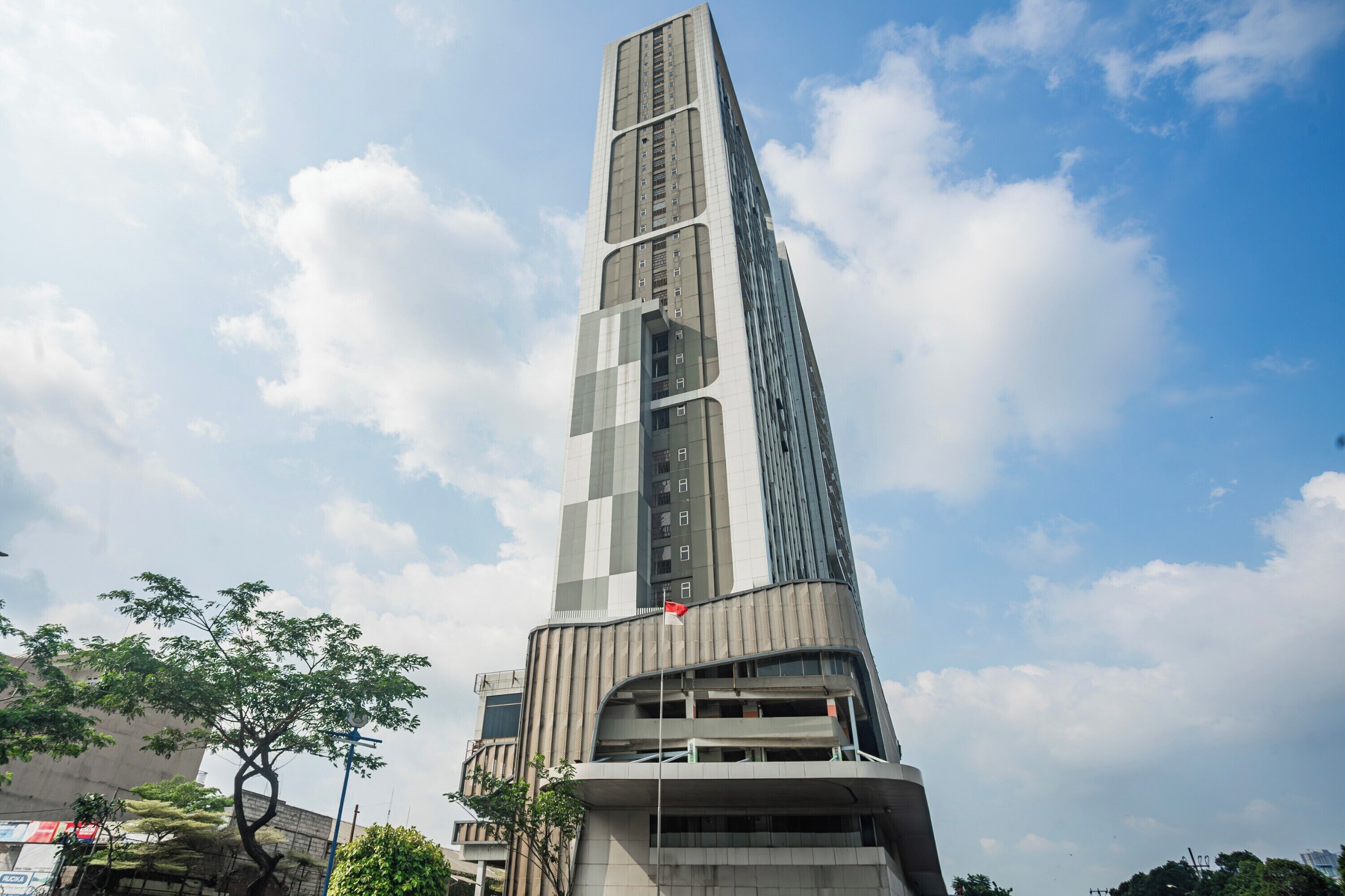 A tall, modern building with a unique architectural design, featuring a prominent flag on top.