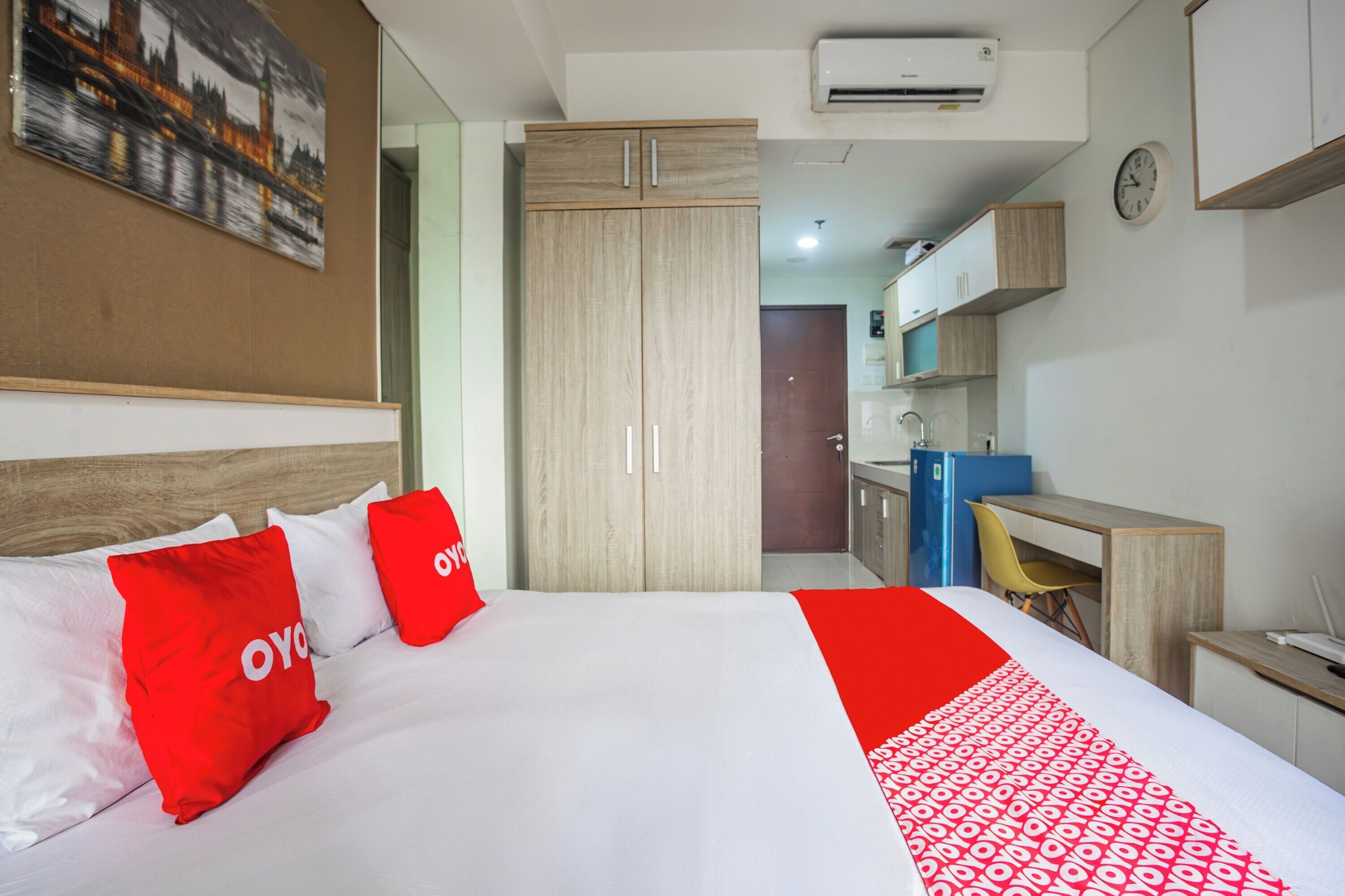 A hotel room with a bed, a desk, and a kitchenette.