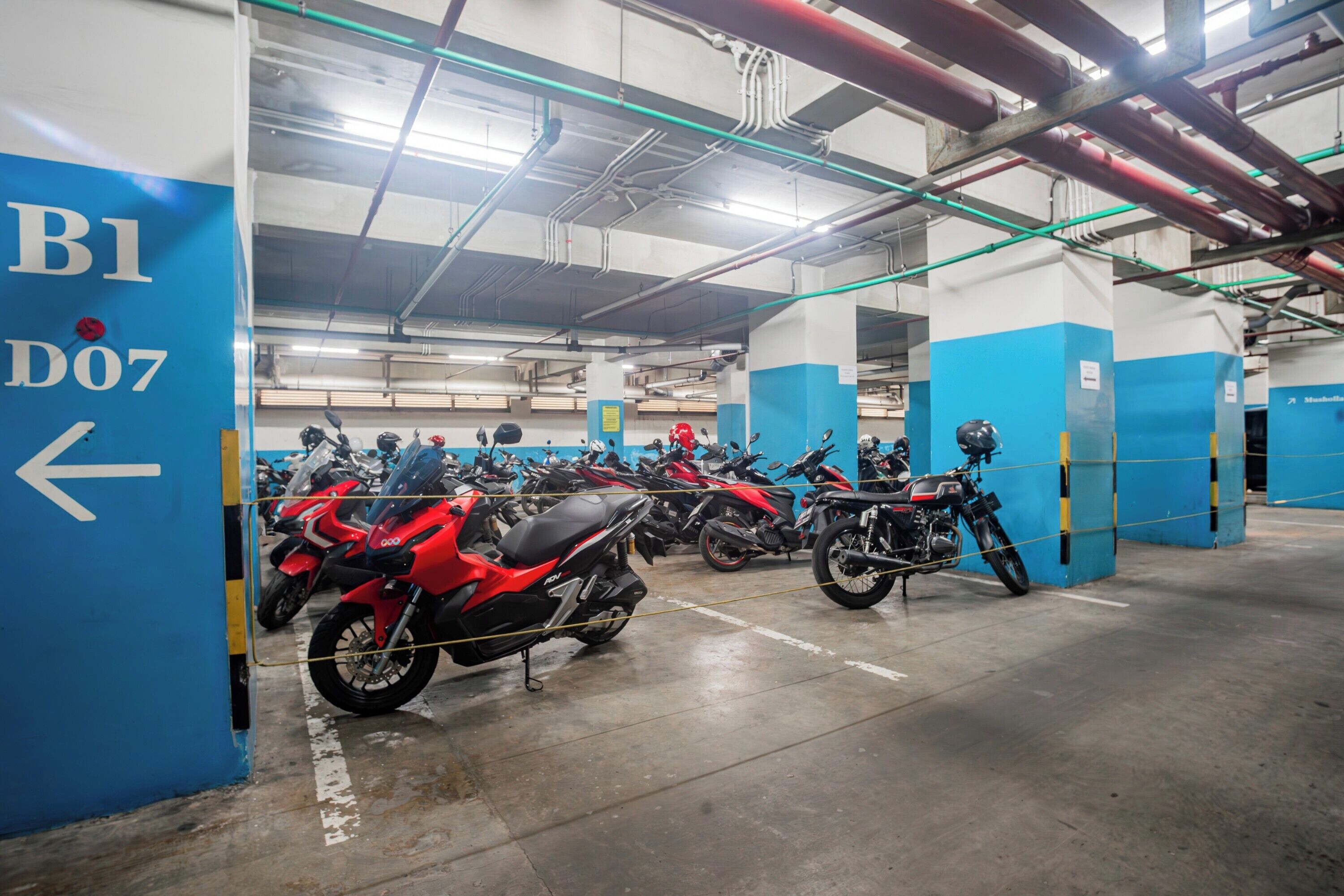 En parkeringsgarage med flere etager, hvor der er parkeret flere motorcykler på anviste pladser.