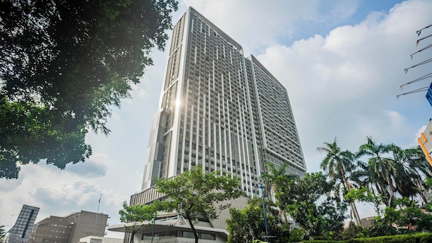 A tall, modern building with a grid-like facade, surrounded by greenery and other contemporary structures. - OYO 94064 Sayy Rooms At Springwood (Tangerang)