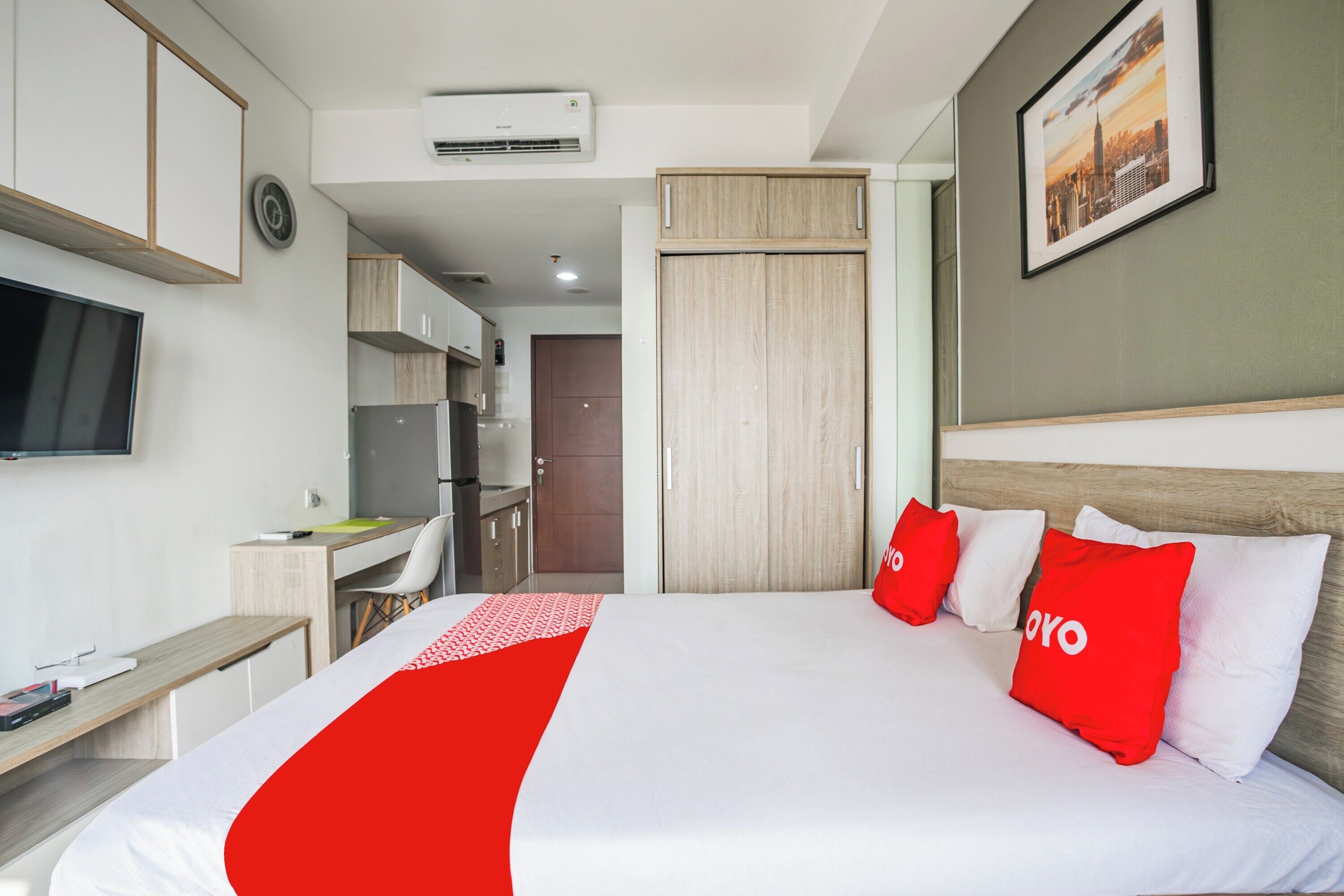 A hotel room with a bed, a desk, a chair, a TV, and a wardrobe.