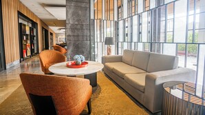 A modern lobby with a sofa, chairs, a coffee table, and a large window offering a view. - OYO 94064 Sayy Rooms At Springwood (Tangerang)
