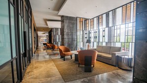 A modern lobby with a long corridor, seating area, and large windows. - OYO 94064 Sayy Rooms At Springwood (Tangerang)