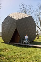 Uma grande estrutura de madeira com formato hexagonal e uma porta.