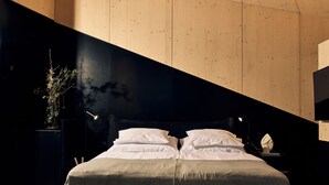 A modern bedroom with a bed, bedside tables, and a nightstand. - Rock Cabins (Vigántpetend)