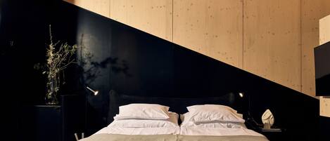 Un dormitorio moderno con cama, mesitas de noche y un pequeño mueble auxiliar.