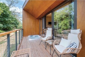 A wooden deck with wicker chairs and a hot tub. - Rock Cabins (Vigántpetend)