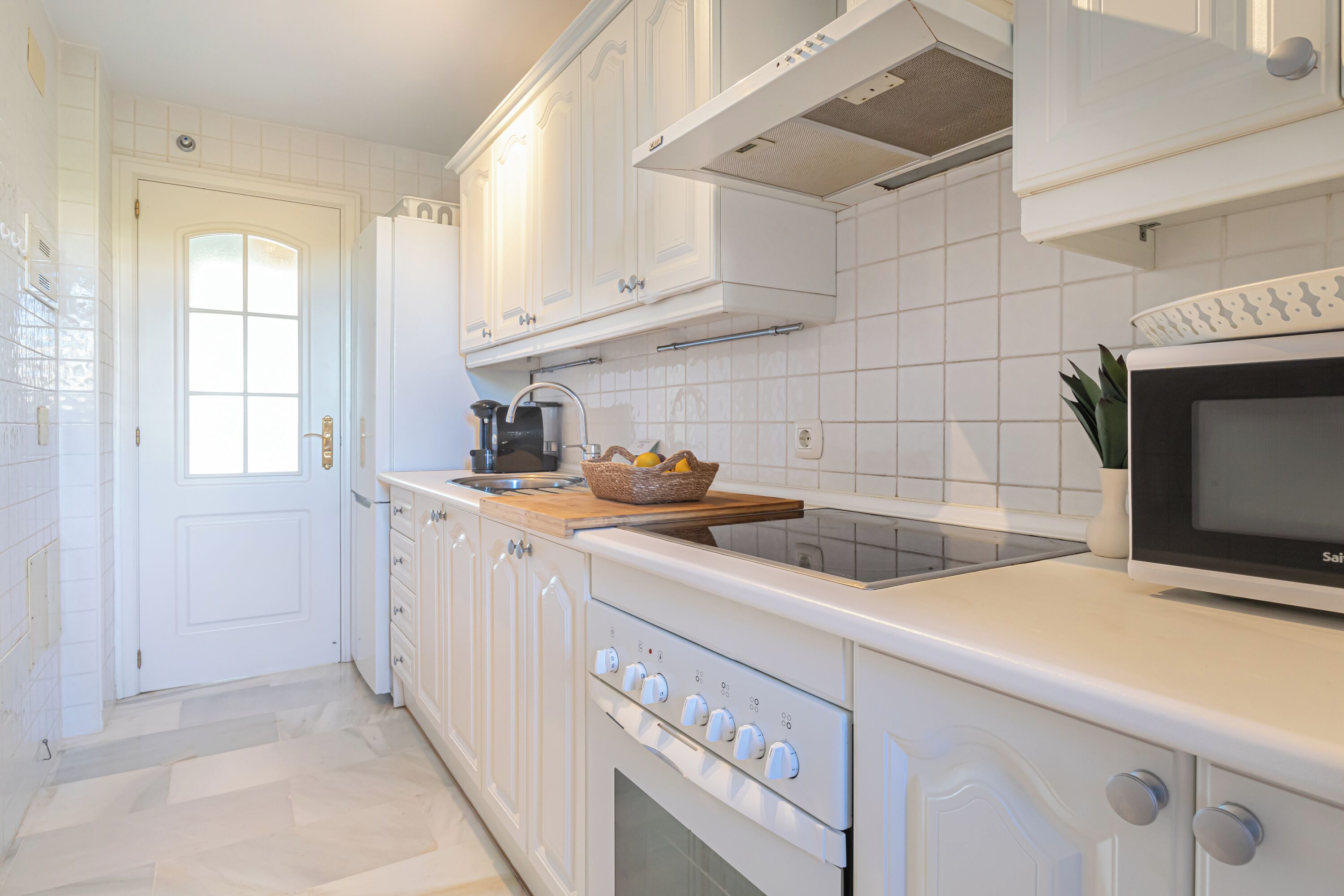 A modern kitchen with white cabinetry, a built-in oven, and a microwave.