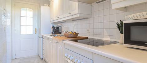 A modern kitchen with white cabinetry, a built-in oven, and a microwave.